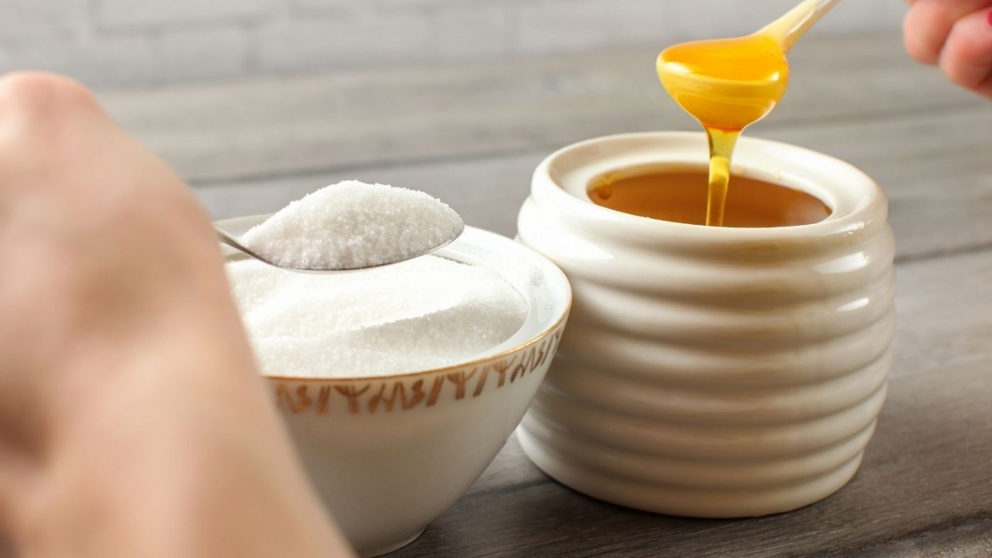 碗里的糖放在碗里的蜂蜜旁边,为Abeeco博客。蜂蜜,健康的、天然的、可替代...