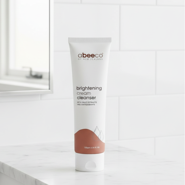 Tube of abeecco brightening cream cleanser on a wooden surface with decorative flowers in the background