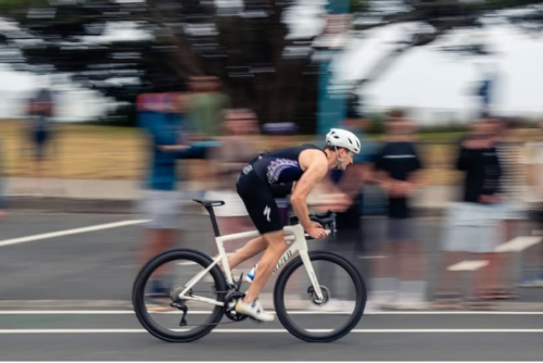 Person riding a bicycle on a road with spectators in the background