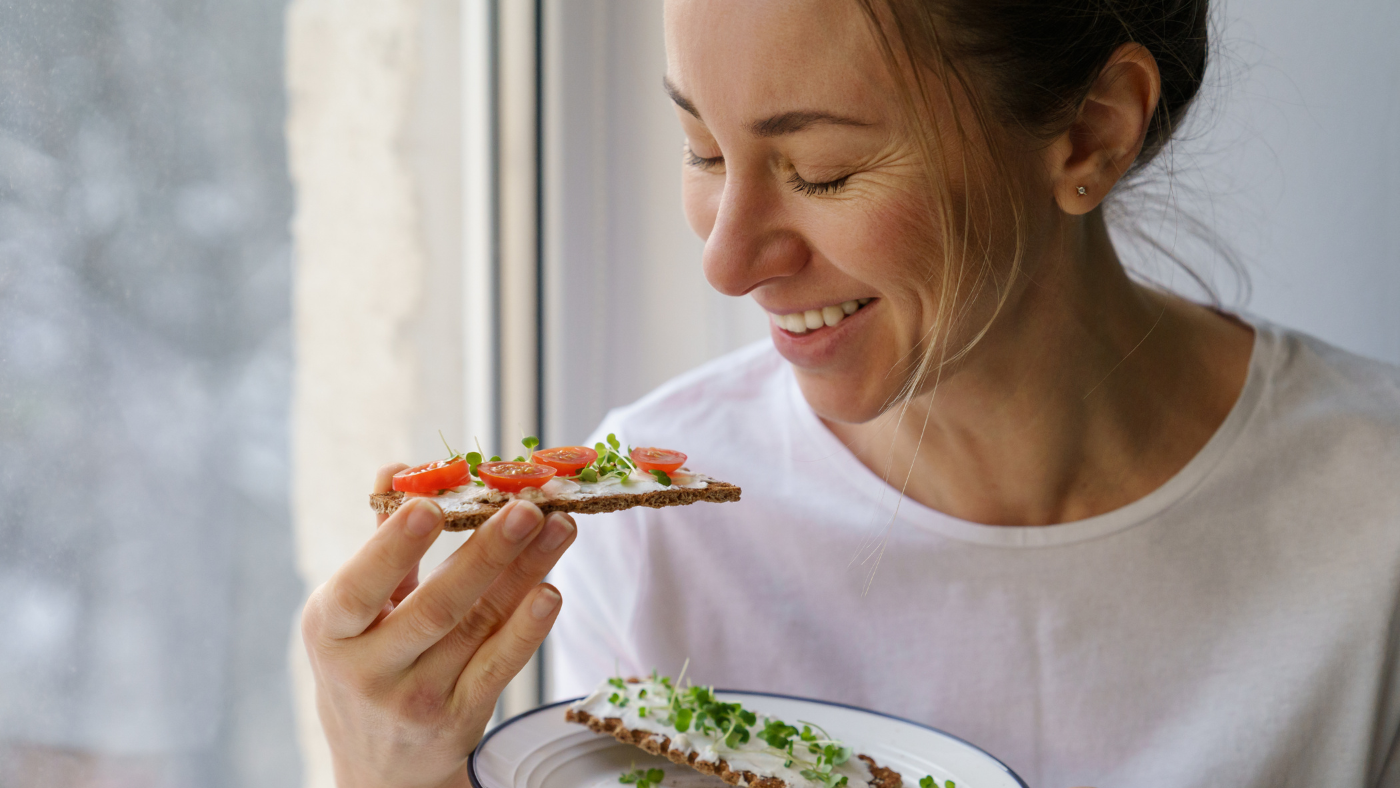 Lady eating a healthy snack with a window behind her