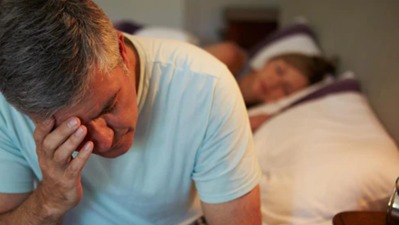 man awake in bed suffering with insomnia