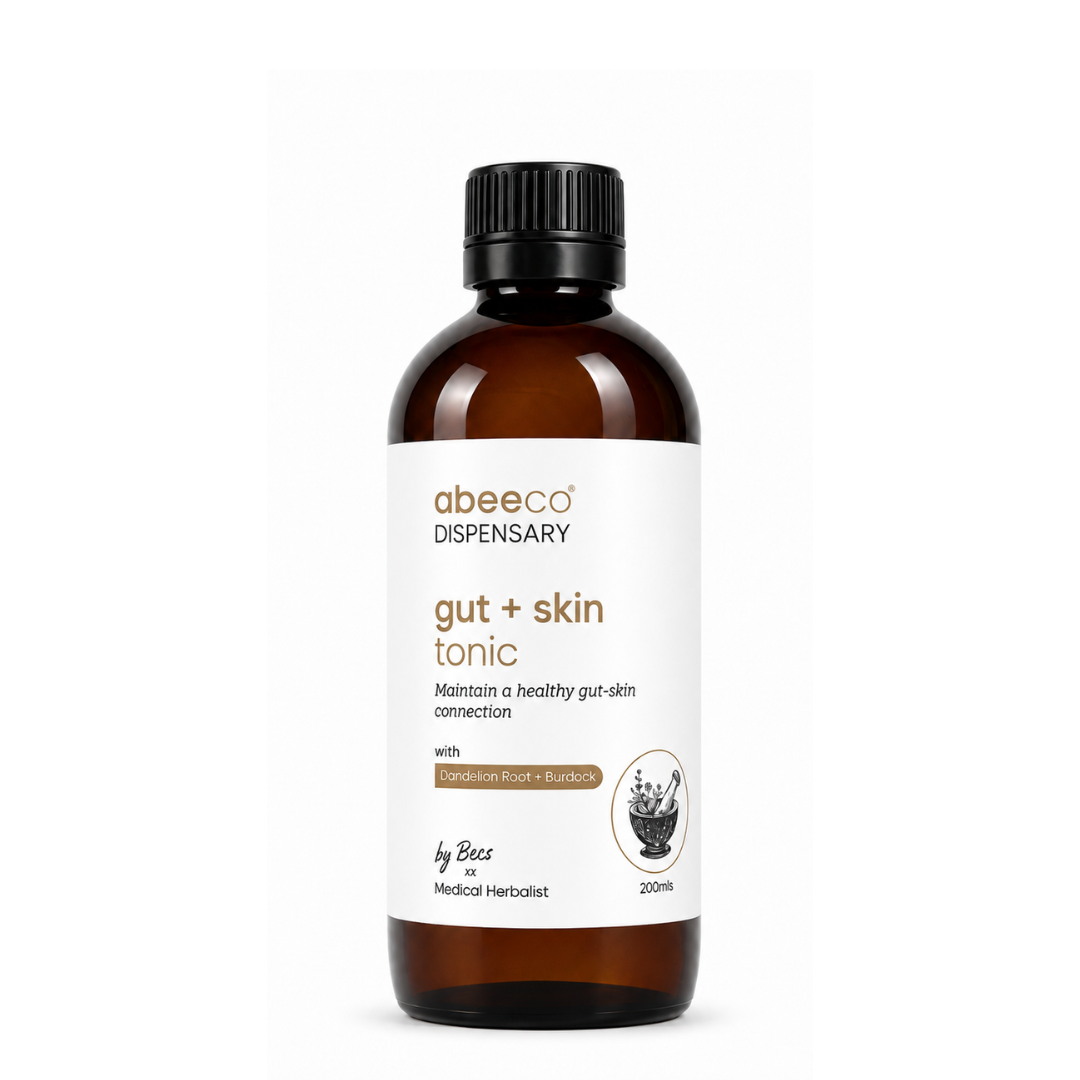 An amber glass bottle of abeeco Dispensary gut + skin tonic with a black cap and white label, centered on a plain white background.