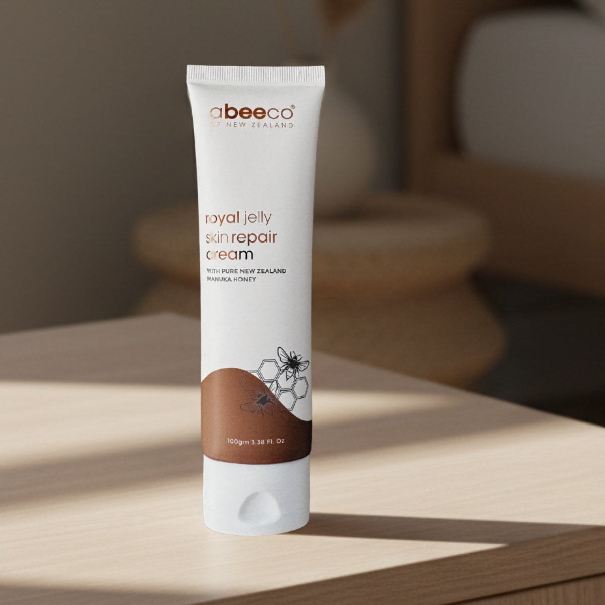 Tube of abeeco royal jelly skin repair cream on a wooden surface with a blurred background
