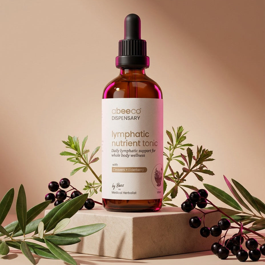 Bottle of lymphatic nutrient tonic with a dropper on a beige background with green leaves and berries.